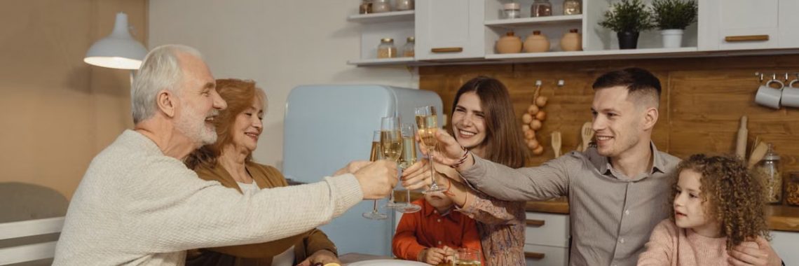 A joyful family toasting at a dinner table indoors, celebrating a special occasion.